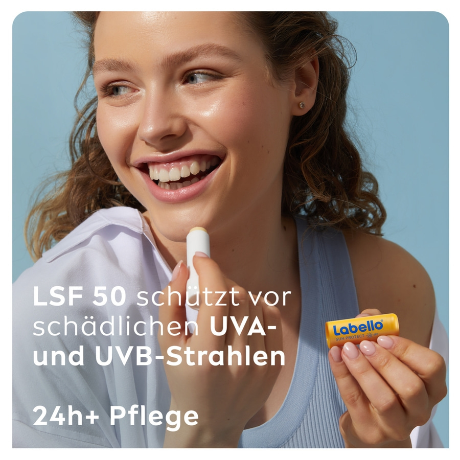 Frau trägt Lippenbalsam mit LSF 50 auf, der vor UVA- und UVB-Strahlen schützt und 24 Stunden Pflege bietet.