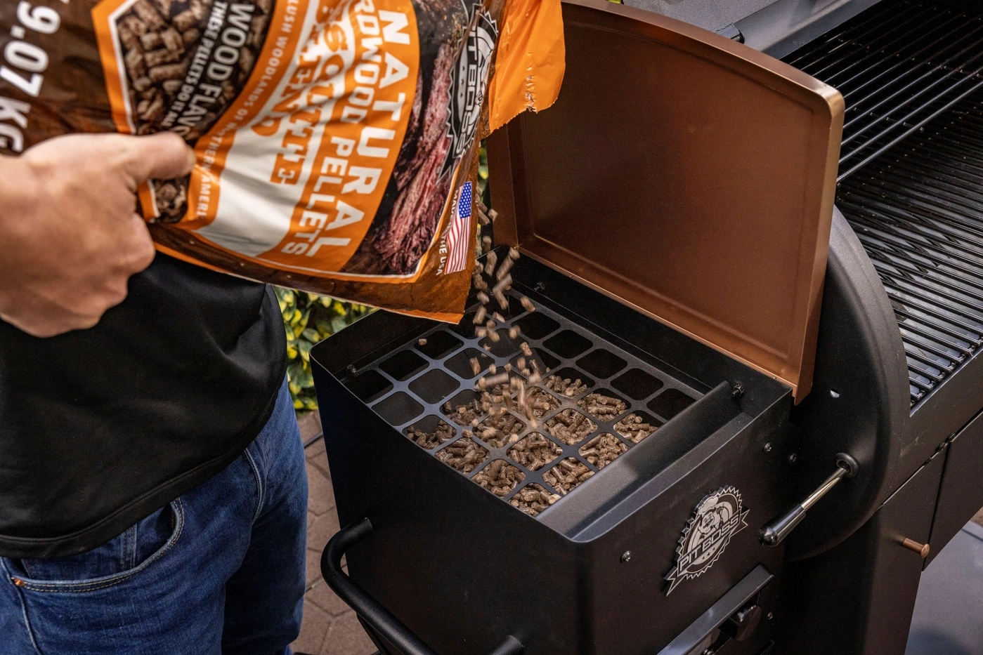 Holzpellets werden in einen Grill geschüttet