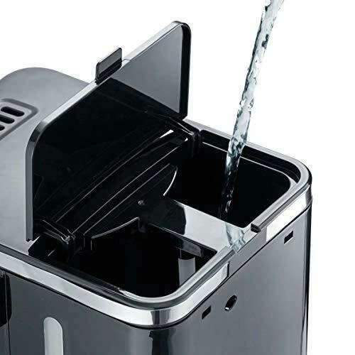 Wasser gießt in einen schwarzen Kaffeemaschinenbehälter, Deckel offen.