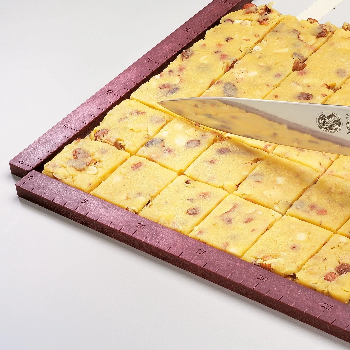 Kuchenstücke werden mit einem Messer auf einem Schneidebrett geschnitten.