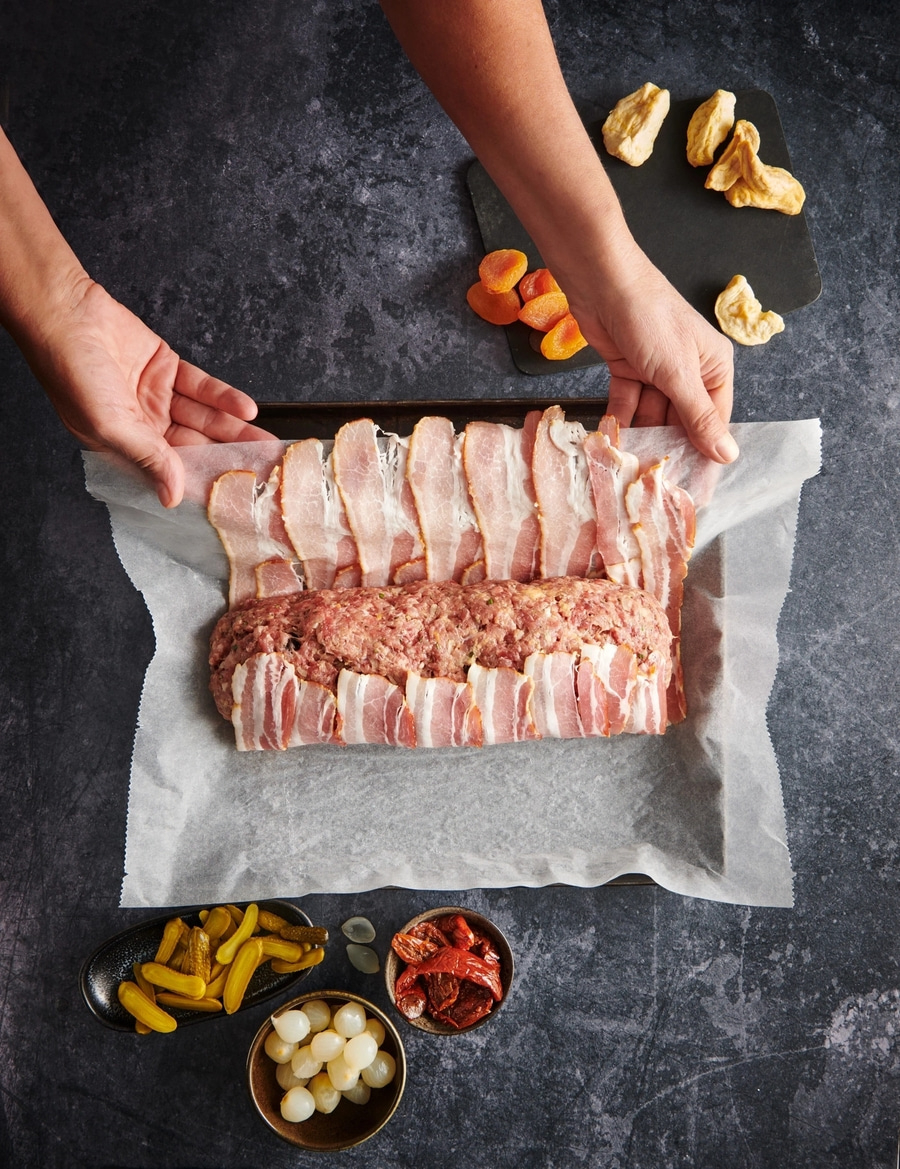 Hackbraten mit Speck umwickelt, Zutaten, Hände, dunkler Hintergrund, Essen