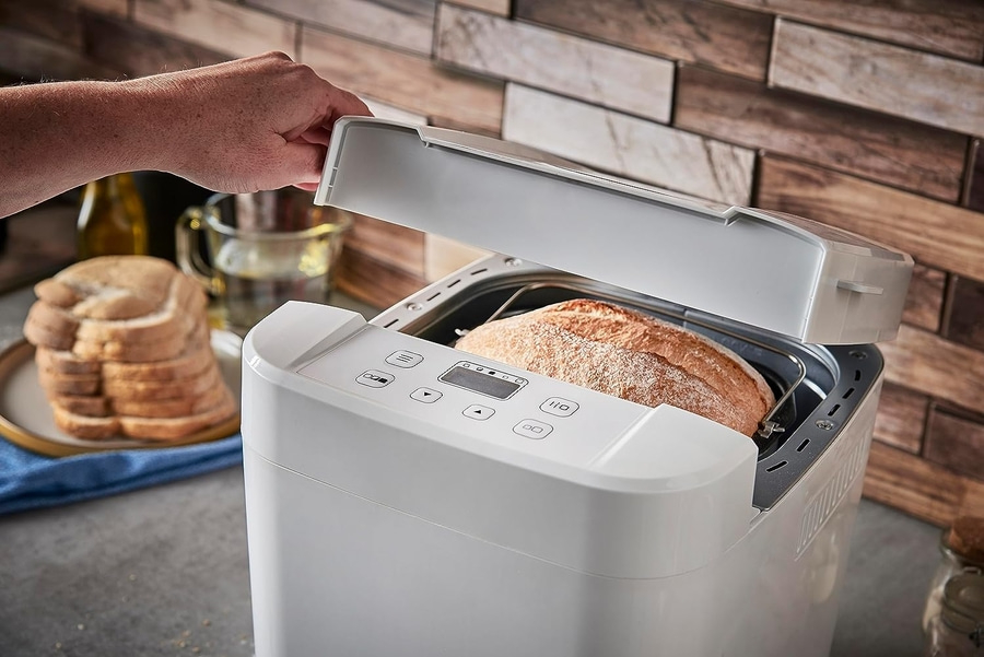 Brotbackautomat mit frisch gebackenem Brot, Hand öffnet den Deckel
