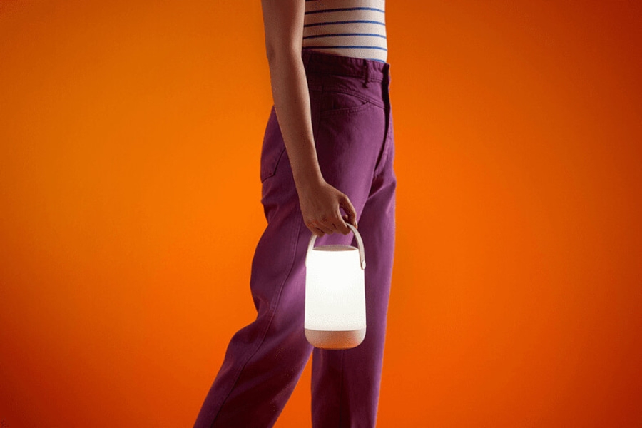 Person hält eine leuchtende Laterne vor orangefarbenem Hintergrund