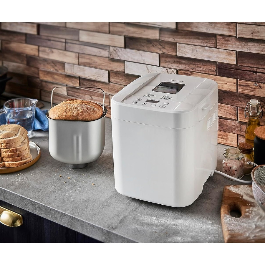 Weißer Brotbackautomat mit Brotlaib und Brot auf einem Teller auf einer Arbeitsplatte