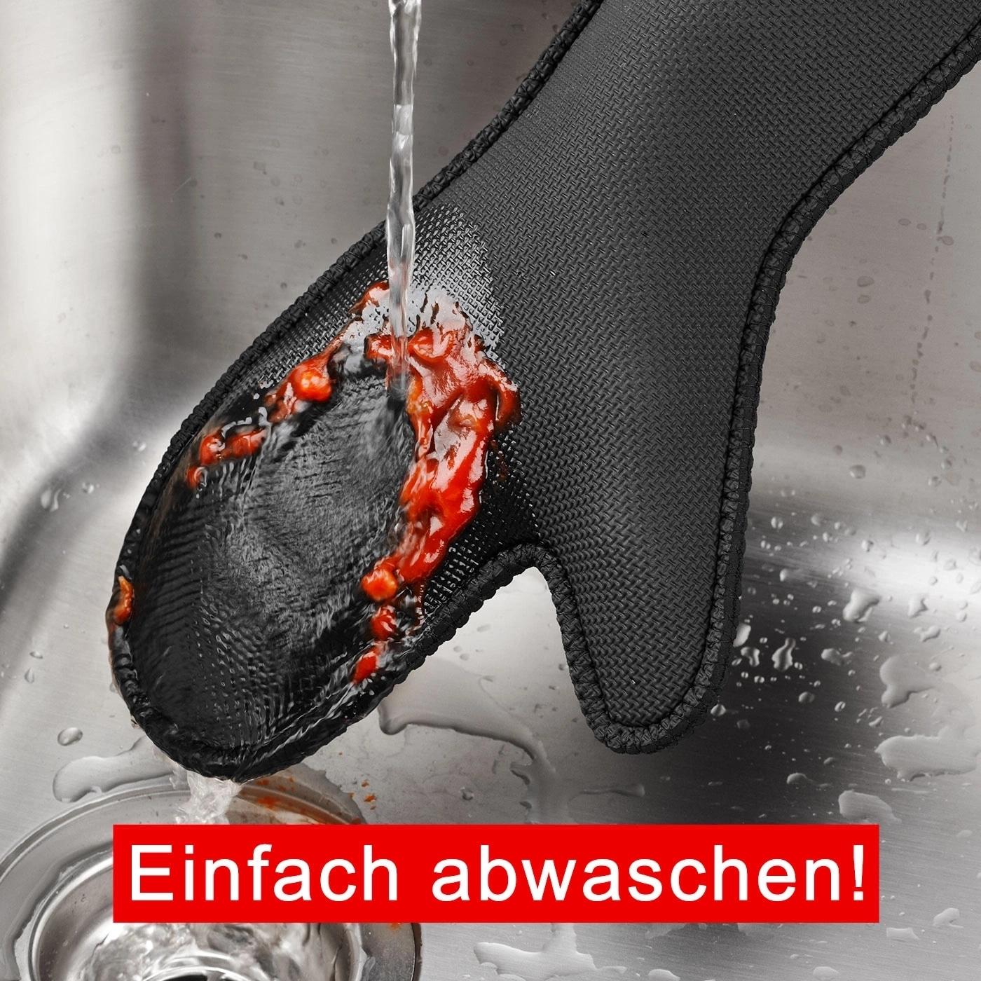 Schwarzer Topfhandschuh wird unter fließendem Wasser gereinigt, mit roter Sauce.