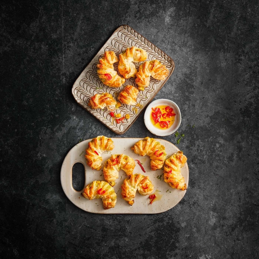 Köstliche, gebackene Croissants mit roter Paprika auf zwei Tellern, daneben Soße.