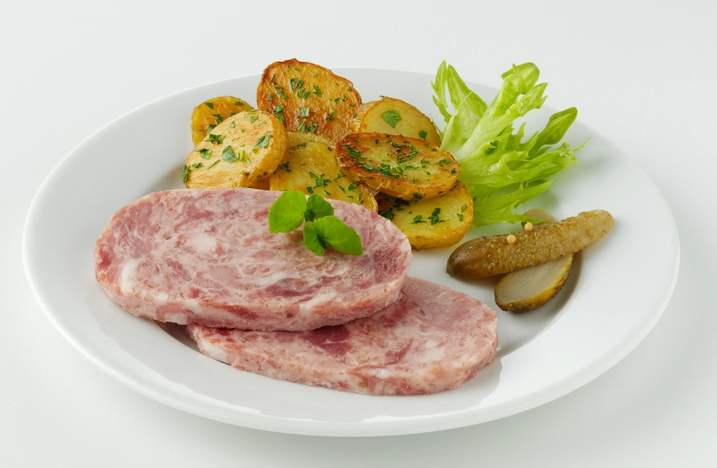 Zwei Scheiben Presskopf mit Bratkartoffeln, Salat und Gewürzgurken