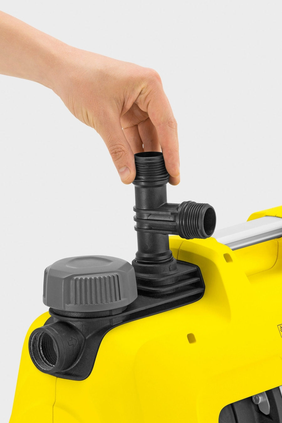 Hand setzt schwarzen Anschluss auf gelbes Gerät. Detailaufnahme.