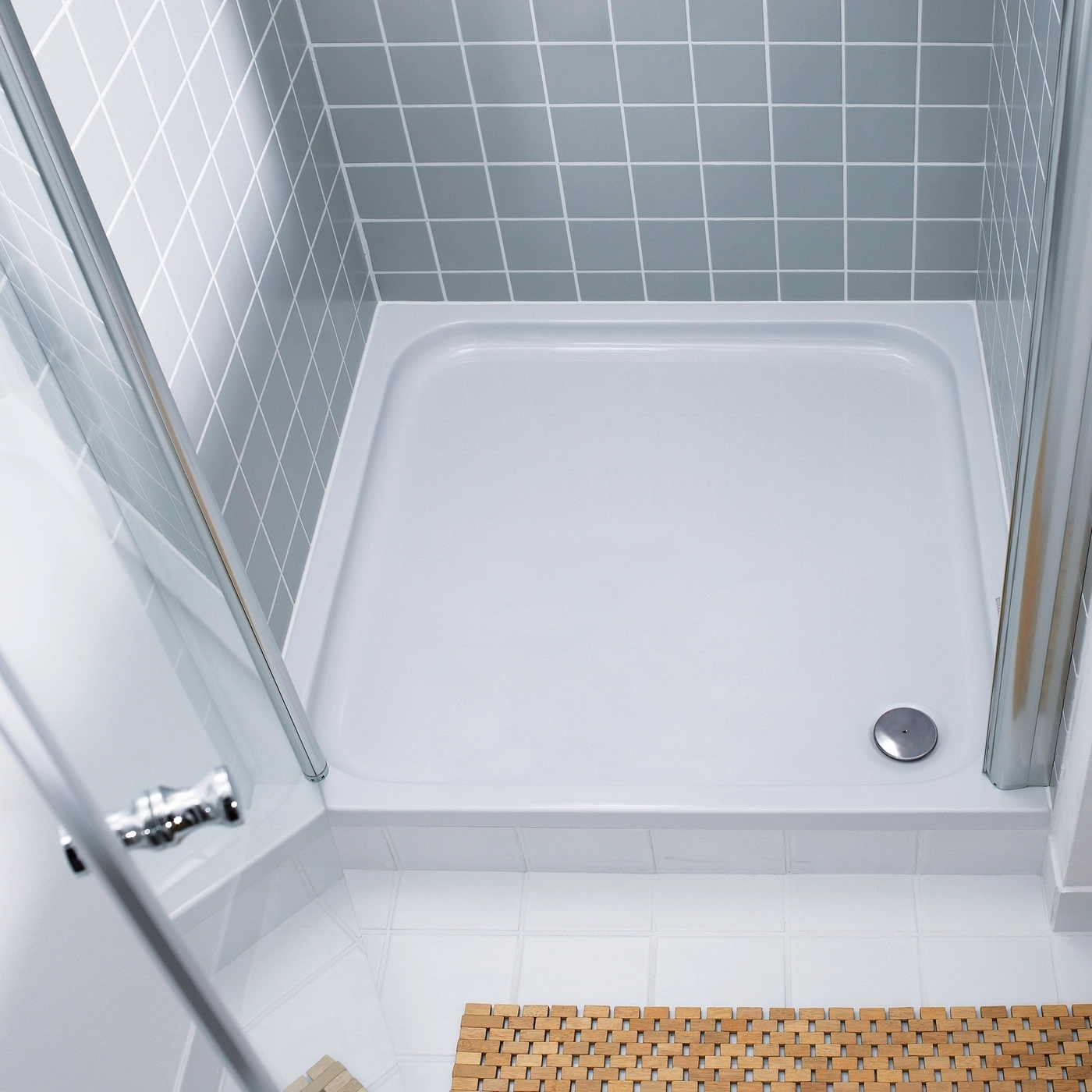 Dusche mit grauen Fliesen und Holzbadezimmerteppich