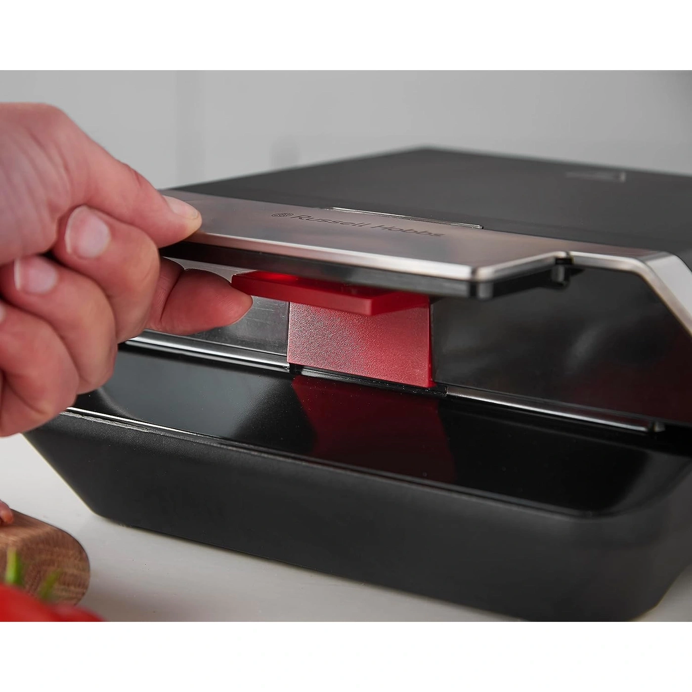 Nahaufnahme eines schwarzen Toasters mit rotem Einsatz, der geöffnet wird.
