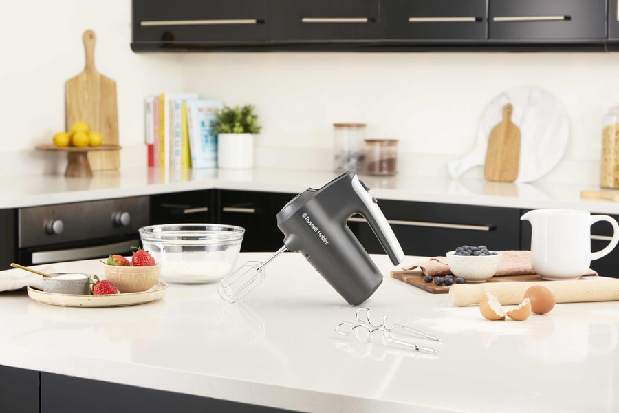 Küchenszene mit Handmixer, Zutaten und Backutensilien auf einer Arbeitsplatte
