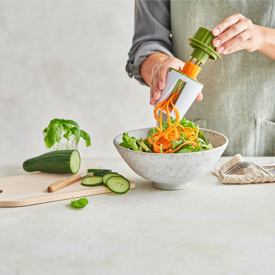 Person schneidet Gemüse mit Spiralschneider in einer Schüssel