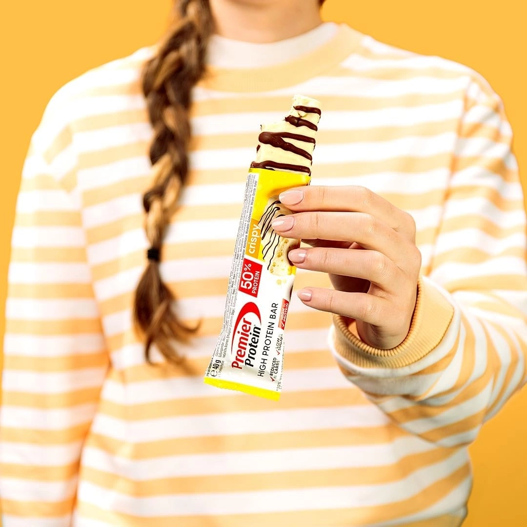 Frau hält Premier Protein Riegel mit Schokoladenüberzug