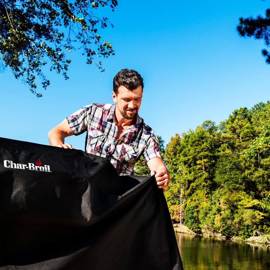 Mann mit Char-Broil-Abdeckung am See, sonniger Tag, Natur, Wald, Himmel