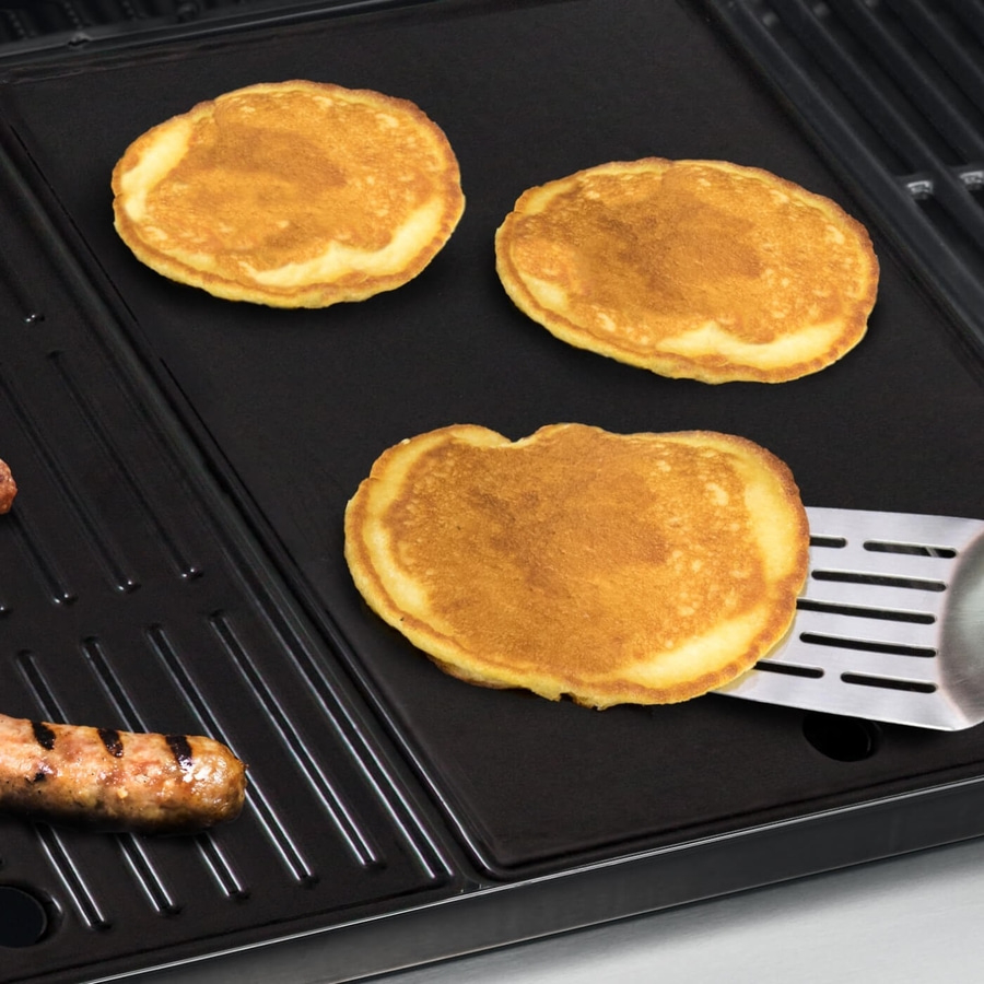 Pfannkuchen auf einer Grillplatte mit Wurst und Pfannenwender