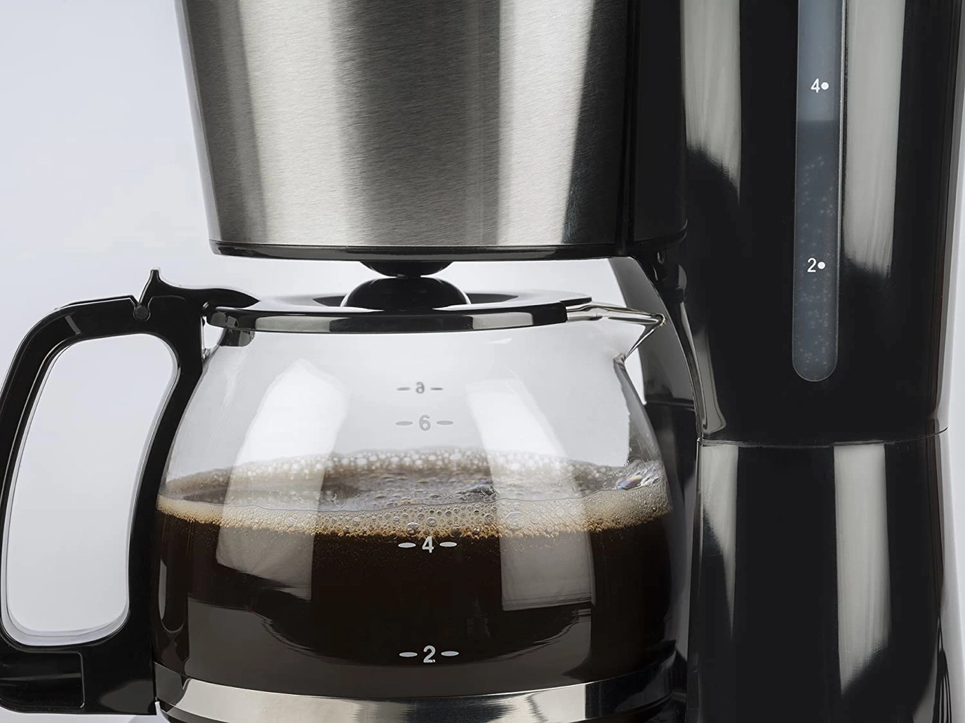 Kaffeemaschine mit Kaffeekanne, gefüllt mit Kaffee, Nahaufnahme, schwarz und silber