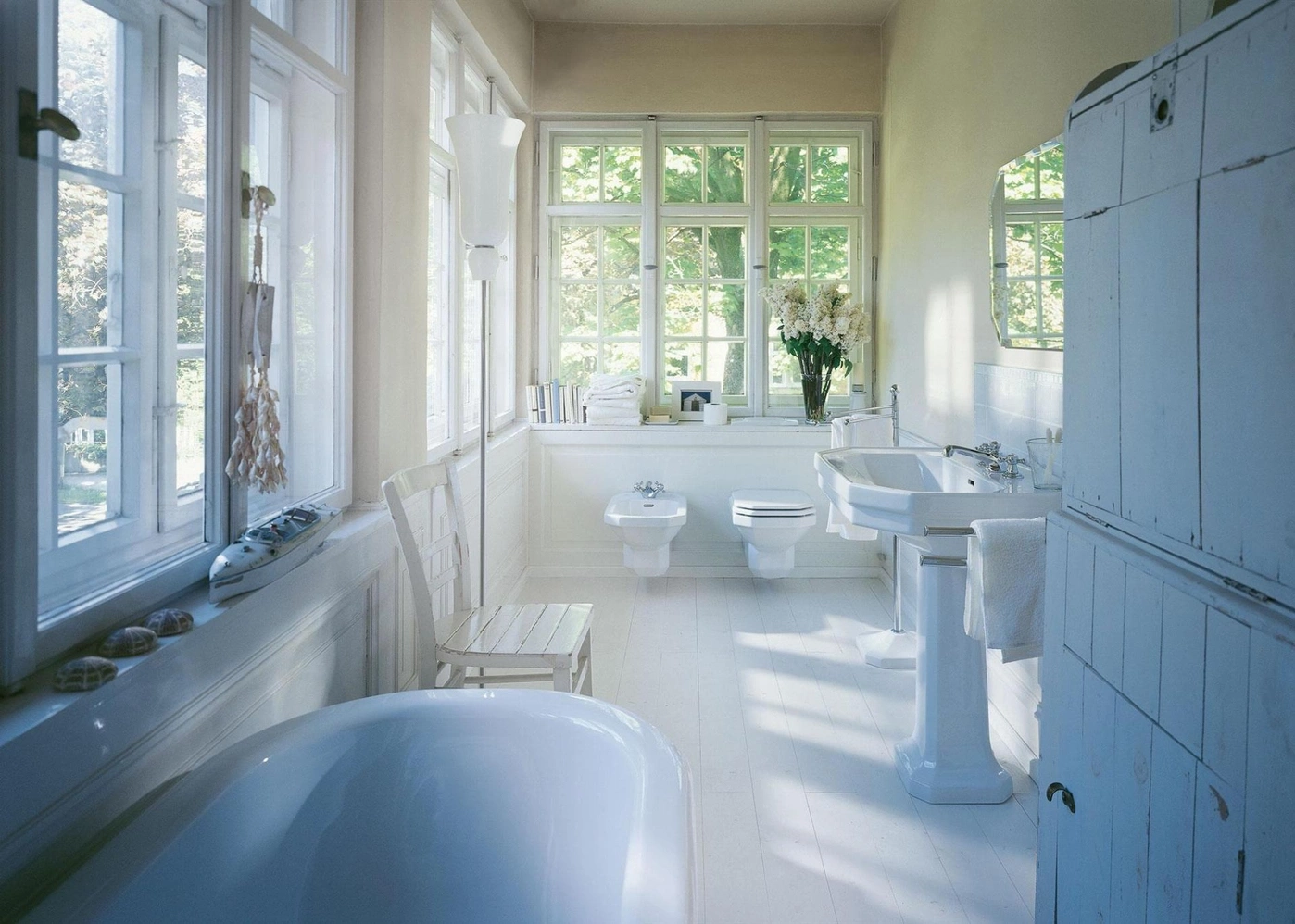 Helles Badezimmer mit Badewanne, Waschbecken, Toilette und Fenster mit Tageslicht.