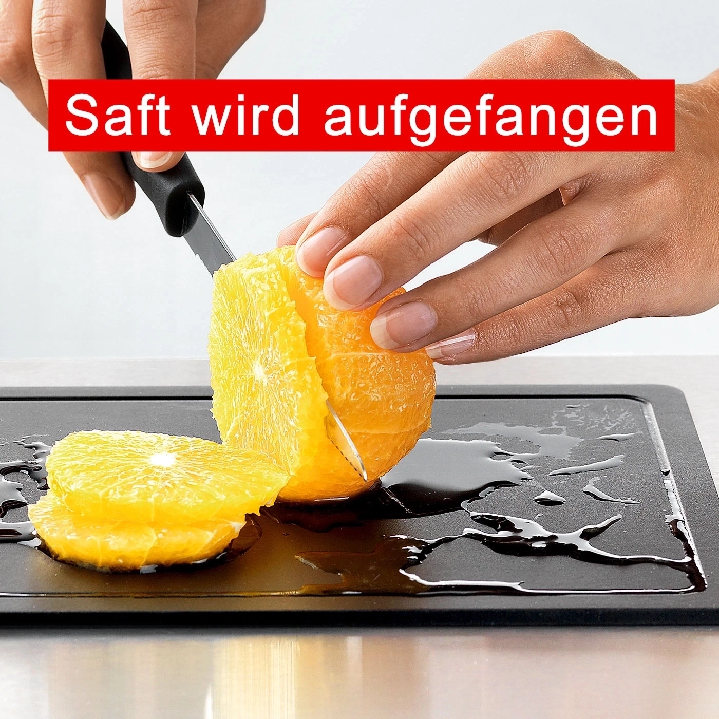 Nahaufnahme einer Person, die eine Orange auf einem Schneidebrett schneidet, Saft wird aufgefangen.