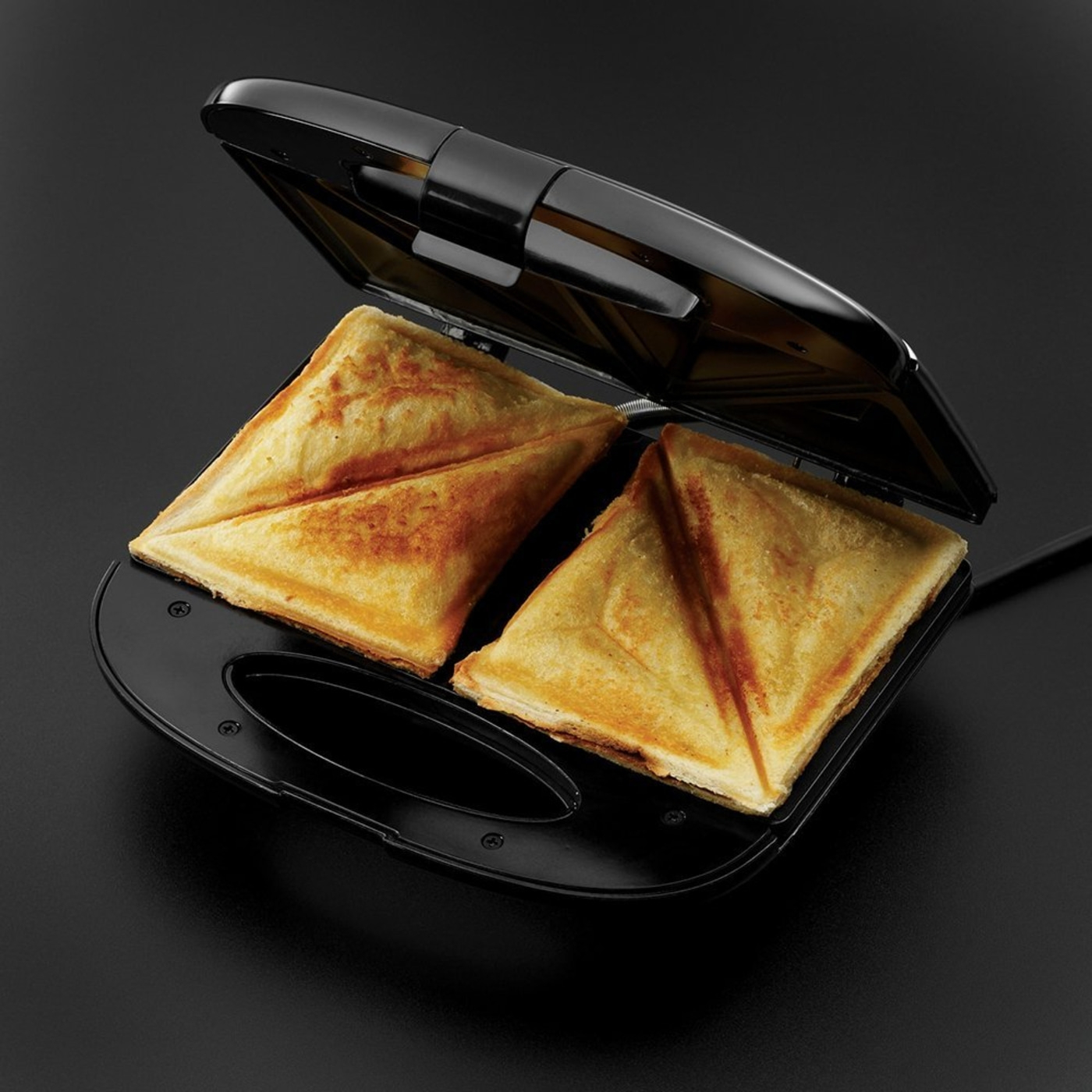 Sandwich-Toaster mit zwei goldenen Sandwiches auf schwarzem Hintergrund