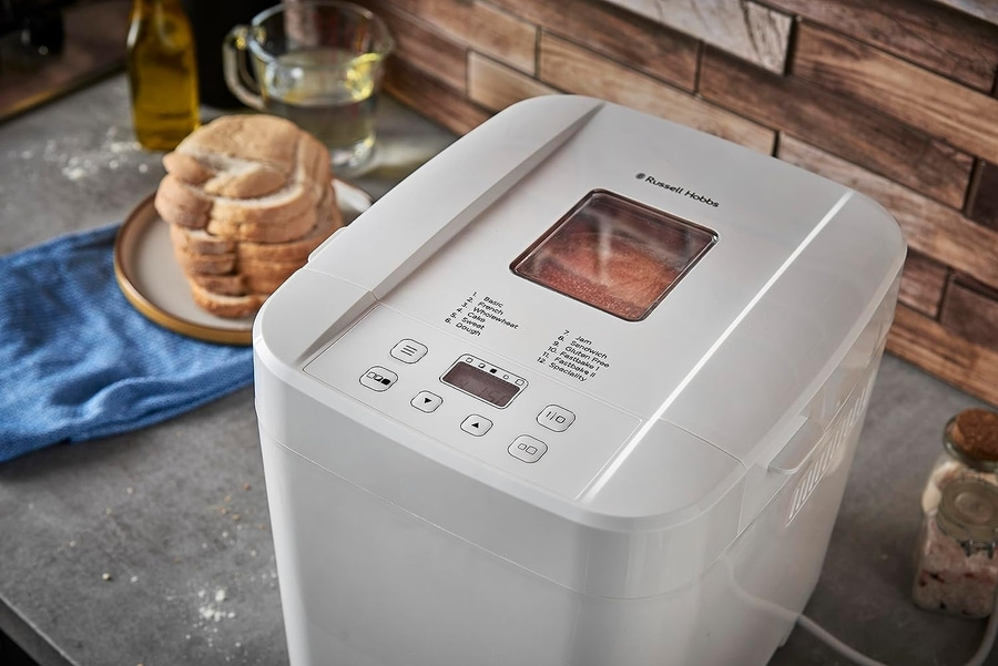 Ein weißer Brotbackautomat mit Bedienfeld und Brotlaib daneben. Russell Hobbs.